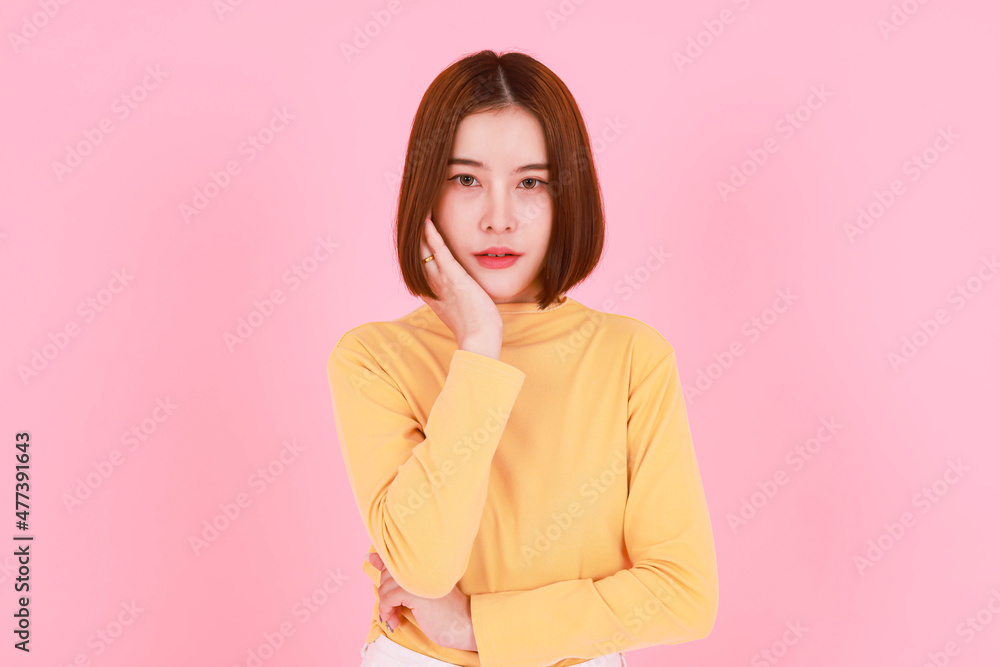 Portrait studio cutout shot of Asian young pretty short hair female model in yellow long sleeve shirt stand smile look at the camera on pink background. Portrait studio cutout shot of Asian young pretty short hair female model in yellow long sleeve shirt stand smile look at the camera on pink background.