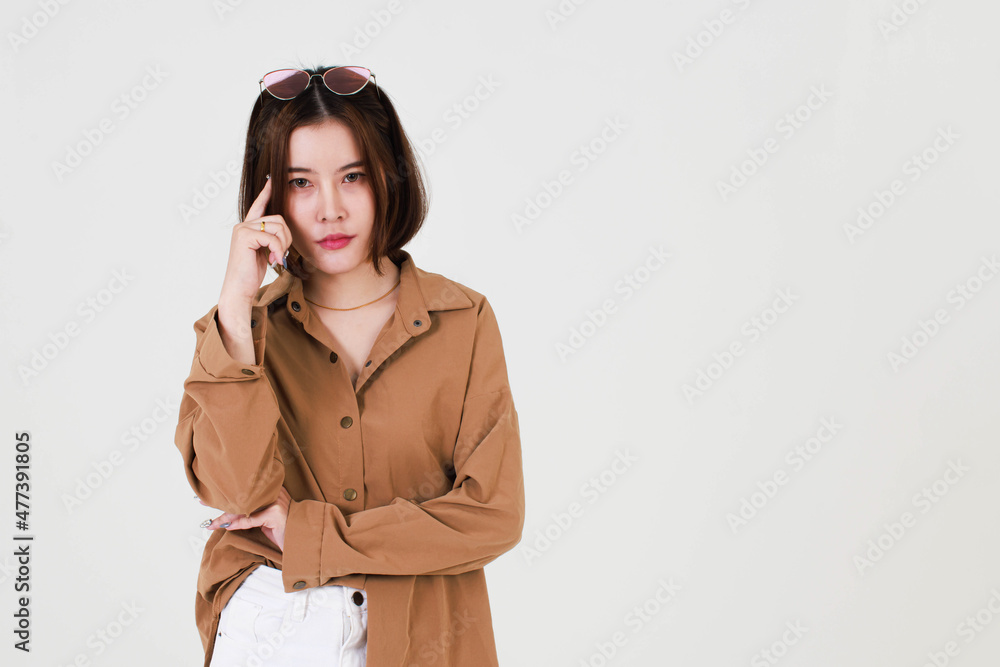 Portrait closeup studio cutout shot of Asian young beautiful short hair female model in brown coat jacket standing smiling look at camera pointing finger up on blank copy space on white background Portrait closeup studio cutout shot of Asian young beautiful short hair female model in brown coat jacket standing smiling look at camera pointing finger up on blank copy space on white background