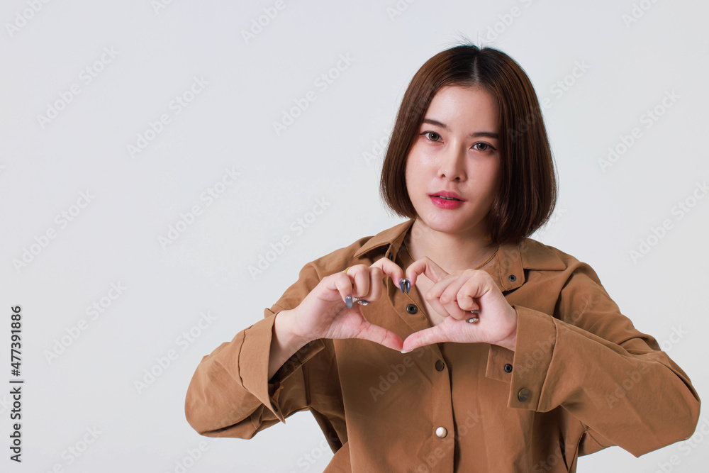 Studio cutout shot of Asian young pretty short hair female model in long brown coat jacket stand smile crossed arm hold thumb up pointing presenting product on blank copy space on white background Studio cutout shot of Asian young pretty short hair female model in long brown coat jacket stand smile crossed arm hold thumb up pointing presenting product on blank copy space on white background