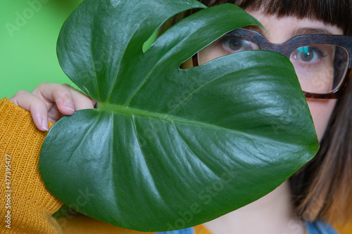 Portrait of woman with eyeglasses covering her face with tree leaf photo