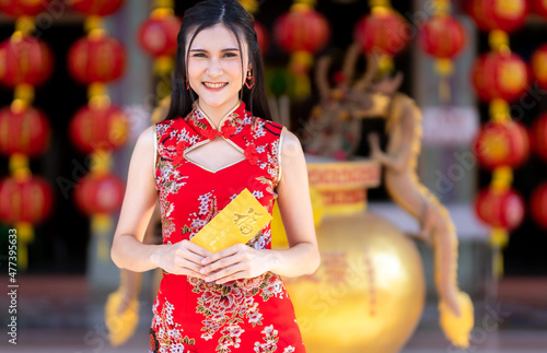 Portrait Asian young woman wearing red cheongsam dress traditional decoration holding yellow envelopes with the Chinese text Blessings written on it Is a Good luck for Chinese New Year Festival