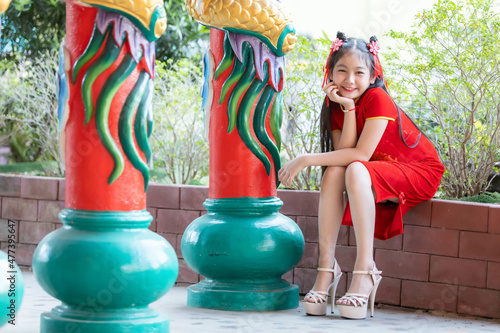 Portrait smiles Cute little Asian girl wearing red cheongsam dress traditional decoration for Chinese new year festival celebrate culture of china at Chinese shrine photo