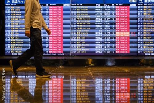 Side view of a man walking beside FIDS at the airport