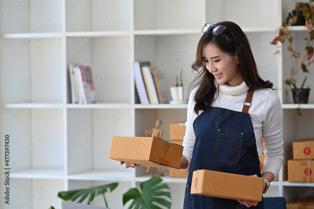 Happy young woman online seller preparing parcel boxes of product for deliver to customer. Happy young woman online seller preparing parcel boxes of product for deliver to customer.