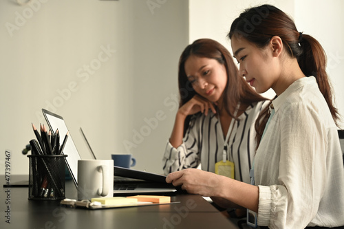 Smiling businesswoman working on project with colleague in modern workplace.