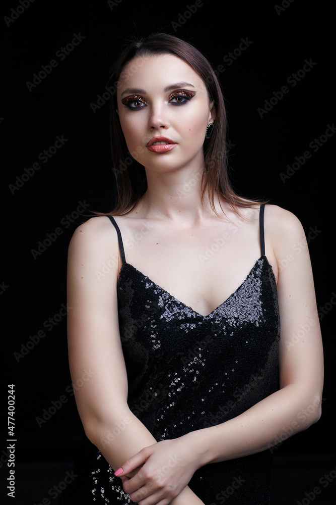 Beautiful young woman in black dress with shining face makeup. Beautiful young woman in black dress with shining face makeup.