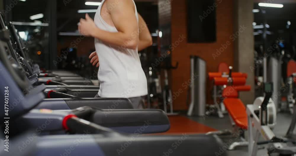 A young man of European appearance running on a treadmill in the gym A young man of European appearance running on a treadmill in the gym