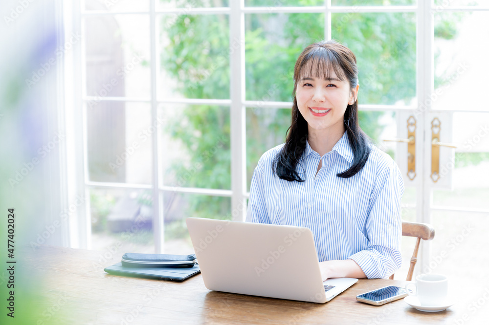 The main visual also has a beautiful woman looking at the camera while working on a computer, with front bokeh and copy space. The main visual also has a beautiful woman looking at the camera while working on a computer, with front bokeh and copy space.