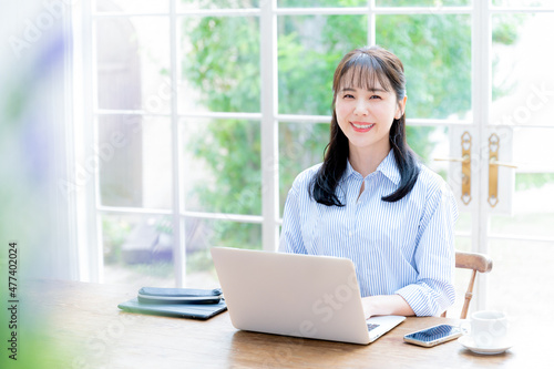 The main visual also has a beautiful woman looking at the camera while working on a computer, with front bokeh and copy space.