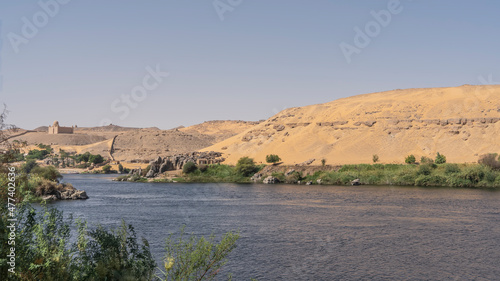 The Blue Nile flows calmly. Along the banks -green vegetation  picturesque boulders. Sand dunes against the azure sky. Egypt