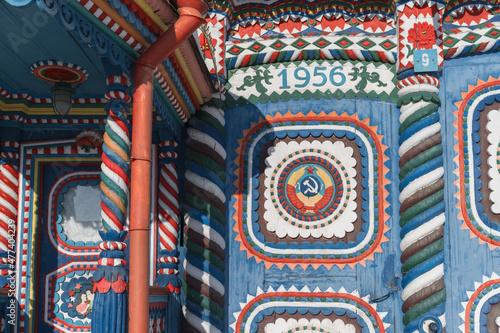 Detail of the porch of a carved multicolored wooden house from the Soviet era in the village of Kunara (Middle Ural, Russia) on a sunny winter day. close-up. Twisted columns, symbols of the USSR 