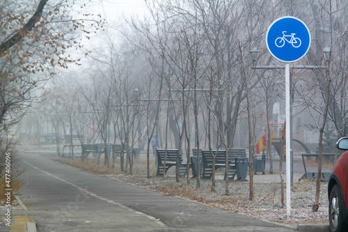 Blue round sign on a pole of bicycle lane in the autumn morning. Bike path