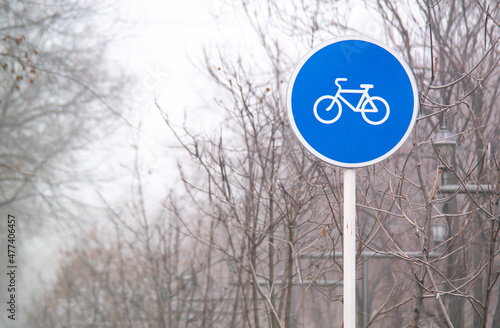 Blue round sign on a pole of bicycle lane in the autumn morning. Bike path