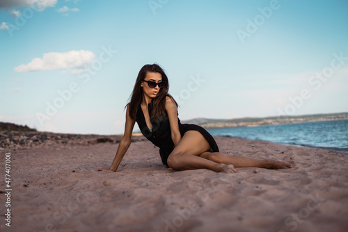 a young woman in a black dress lies on the sand. High quality photo © Сергей Курбатов