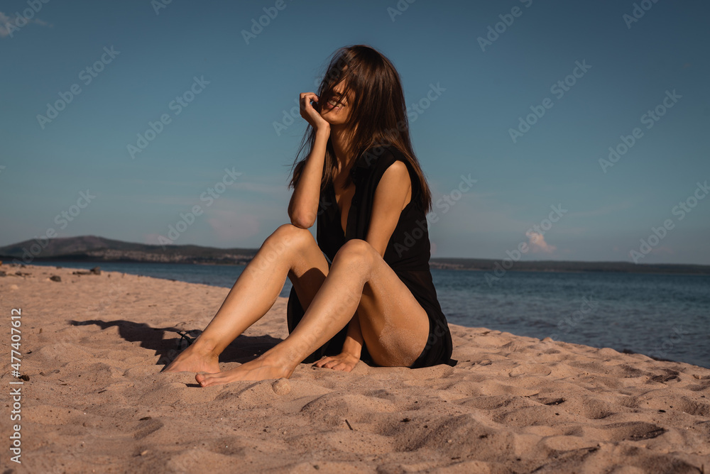 a young woman in a black dress lies on the sand. High quality photo a young woman in a black dress lies on the sand. High quality photo