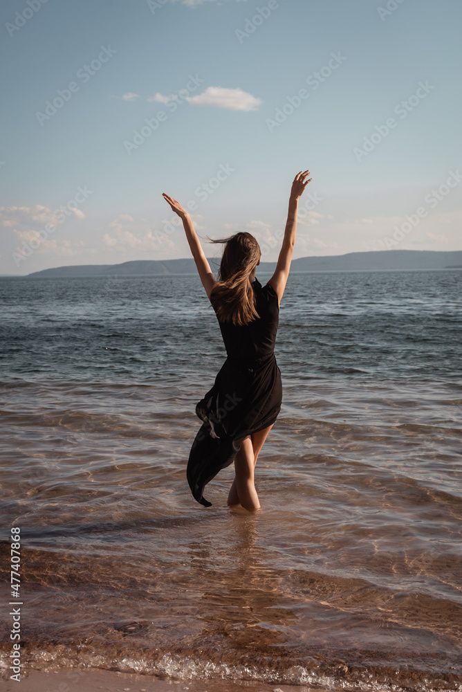 A young woman in a black dress stands in the water by the sea. High quality photo A young woman in a black dress stands in the water by the sea. High quality photo