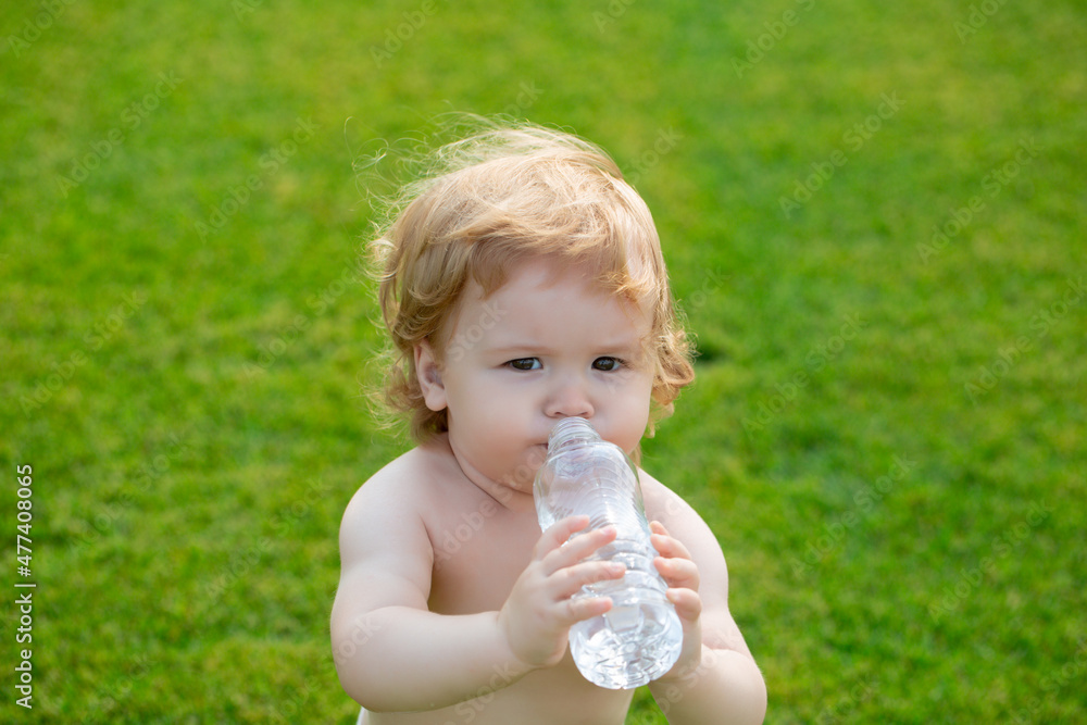 Baby drinking water. Close-up of child baby drinking fresh and pure water from bottle with a blurred green grass background. Baby drinking water. Close-up of child baby drinking fresh and pure water from bottle with a blurred green grass background.
