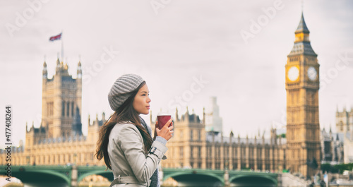 London Asian woman drinking coffee during coronavirus UK travel. Serious professional businesswoman walking having breakfast in England. Banner panoramic of Big Ben background.