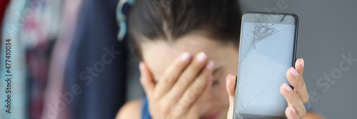 Принти на полотні Sad woman covering her eyes with hand and holding broken mobile phone closeup