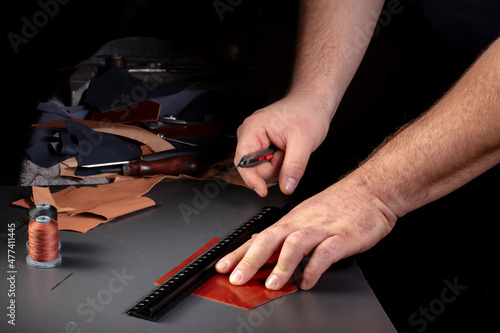 The process of making leather goods. The hands of the master work with a leather product.