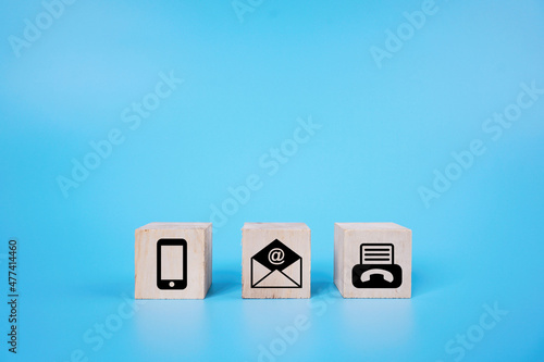 email, phone and fax icon on a square wooden cube over the blue background