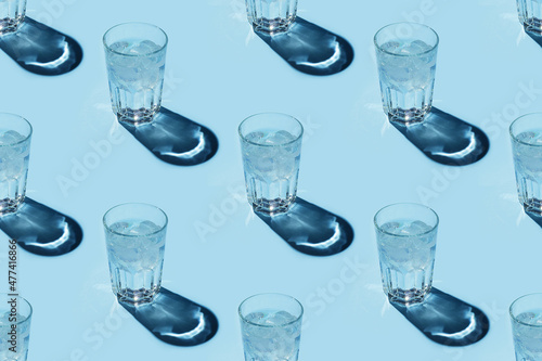 Seamless repetitive pattern with transparent glasses of water with ice cubes on blue background. photo