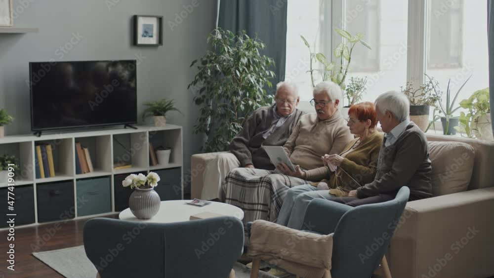 Group of Caucasian senior people using digital tablet and talking sitting on sofa at nursing home Group of Caucasian senior people using digital tablet and talking sitting on sofa at nursing home