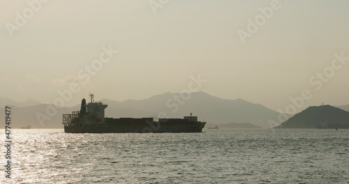 Cargo ship pass though the sea at sunset time