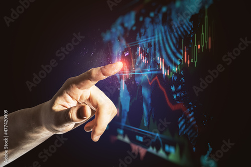Close up of business man hand pointing at abstract glowing blue business forex chart and map interface on dark background. Trade, finance, analysis, growth, technology and innovation concept.