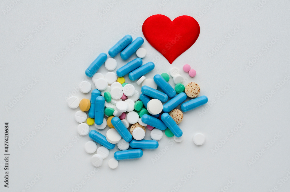 Many different tablets, red heart on white background. Medical flat lay . Valentine's Day. world pharmaceutical day
