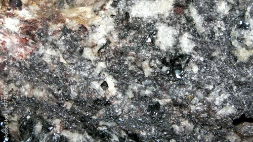 Macro of a quartz-biotite gneiss with quartzitic crystalline layers and zincblende inclusions in a dark rock matrix. photo