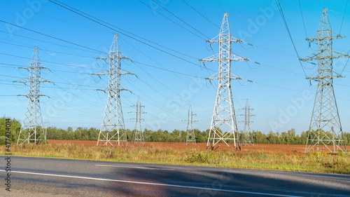 High-voltage power lines and power pylons near the highway. Transmission towers in industrial landscape. High voltage electric transmission towers. © nieriss