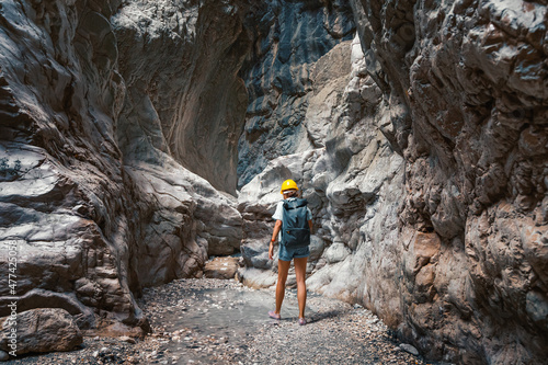 Tableau sur toile Person with helmet and backpack hiking in deep and dark but amazing canyon in mountains