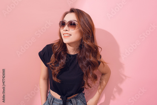 Portrait of smiling beautiful girl in sunglasses against of pink background © makistock