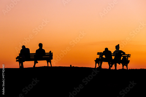 on a hot summer day at sunset people sit on a bench discussing affairs and plans silhouettes of people