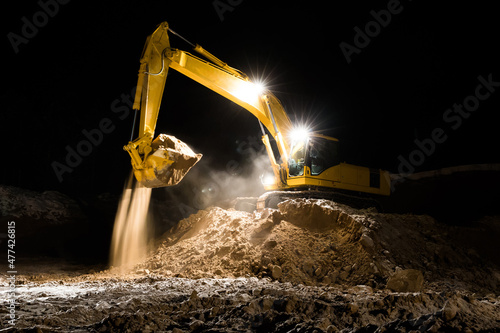 Tractor excavator worker digs a trench on a construction site at night