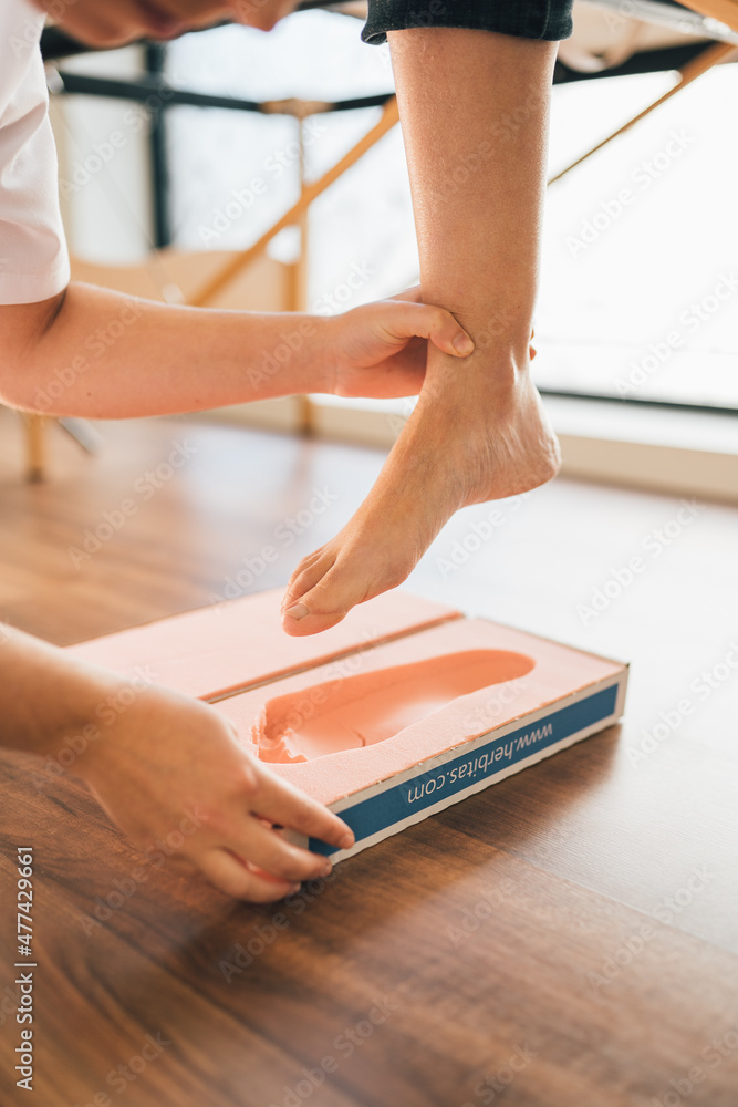 Fototapeta premium Chiropodist taking the shape of a patient's foot with a foam mold for the manufacture of a special insole.