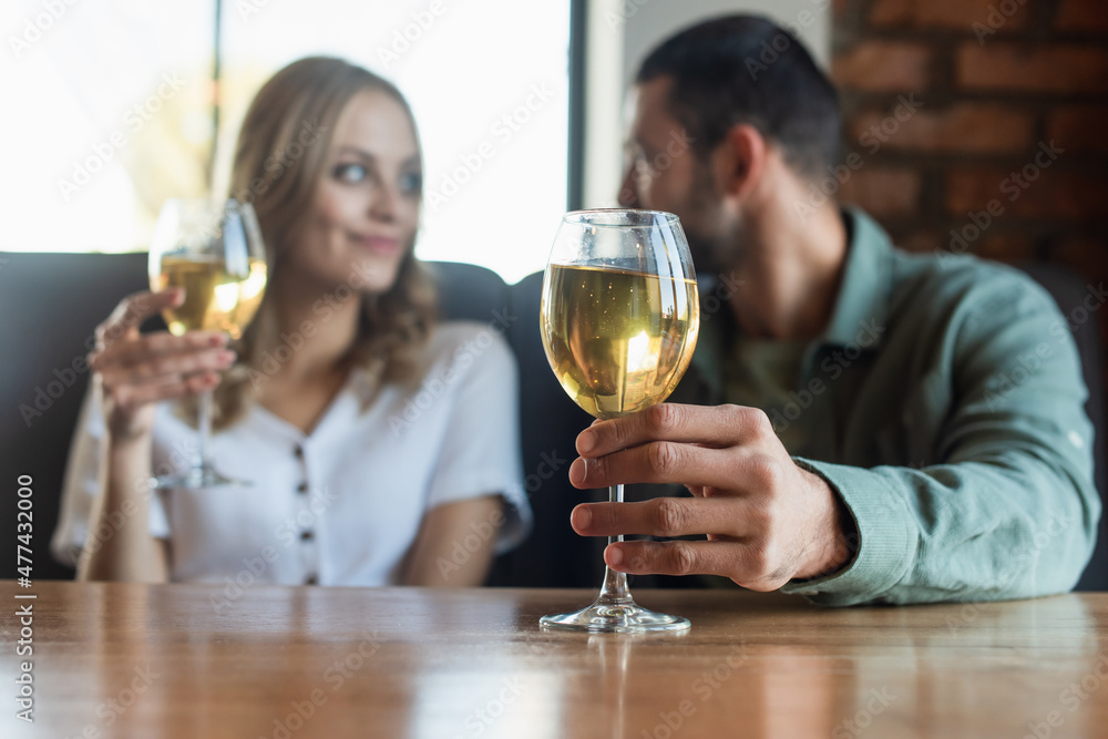 selective focus of glass with white wine near couple having romantic date in cafe selective focus of glass with white wine near couple having romantic date in cafe