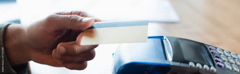 cropped view of man holding credit card near payment terminal in cafe, banner cropped view of man holding credit card near payment terminal in cafe, banner