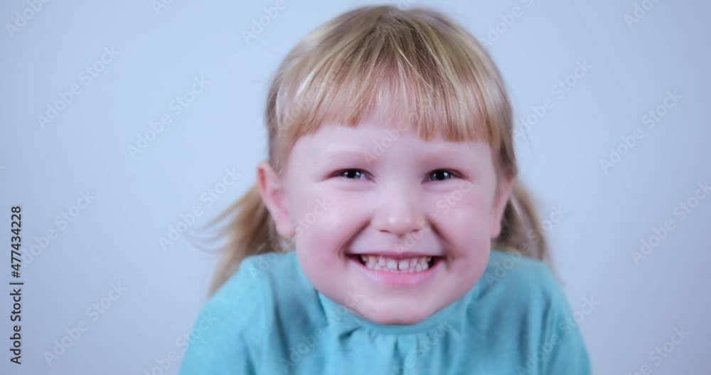 Portrait little blond Girl looking at camera a little shy and smile . Laughs Happily Child. Portrait little blond Girl looking at camera a little shy and smile . Laughs Happily Child.