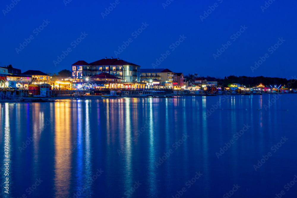 Night lights on the sea shoreline. Resort town view from the sea to the shore.