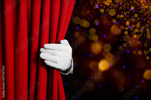 Man opening red front curtain against blurred lights. Bokeh effect