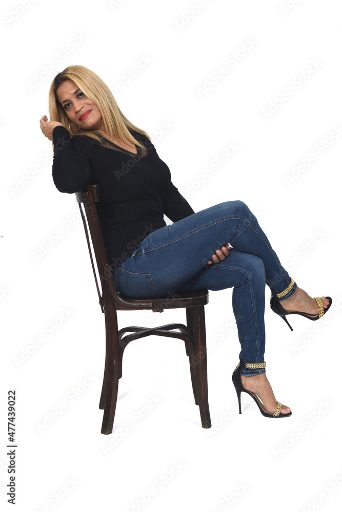 Side view of portrait of a woman with jeans and heeled shoes looking at camera and legs crossed on white background Side view of portrait of a woman with jeans and heeled shoes looking at camera and legs crossed on white background