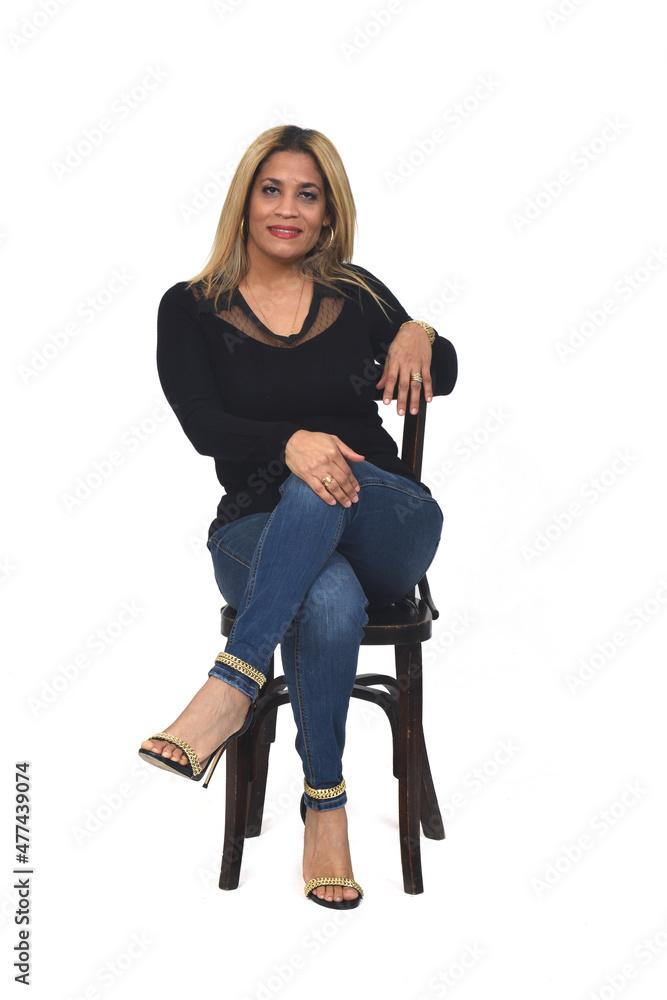 Fototapeta premium front view of portrait of a woman with jeans and heeled shoes looking at camera and legs crossed on white background