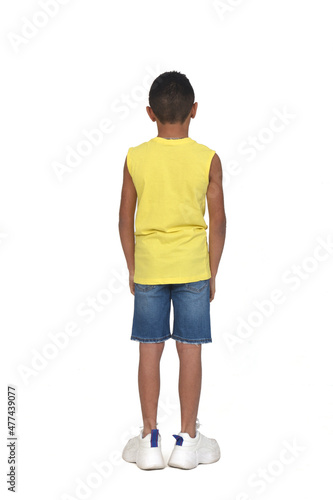 rear view of full portrait of a boy dressed in shorts and sleeveless with arms crossed on white background © curto