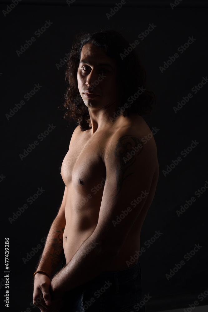 low key portrait of shirtless man looking at camera black background low key portrait of shirtless man looking at camera black background