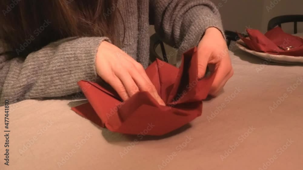 A woman folds napkins for a dinner party A woman folds napkins for a dinner party