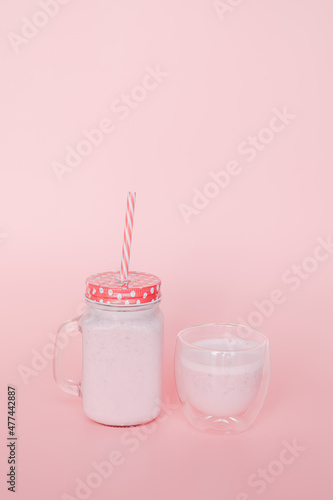 Strawberry milk filled with strawberries in front of the pink background.