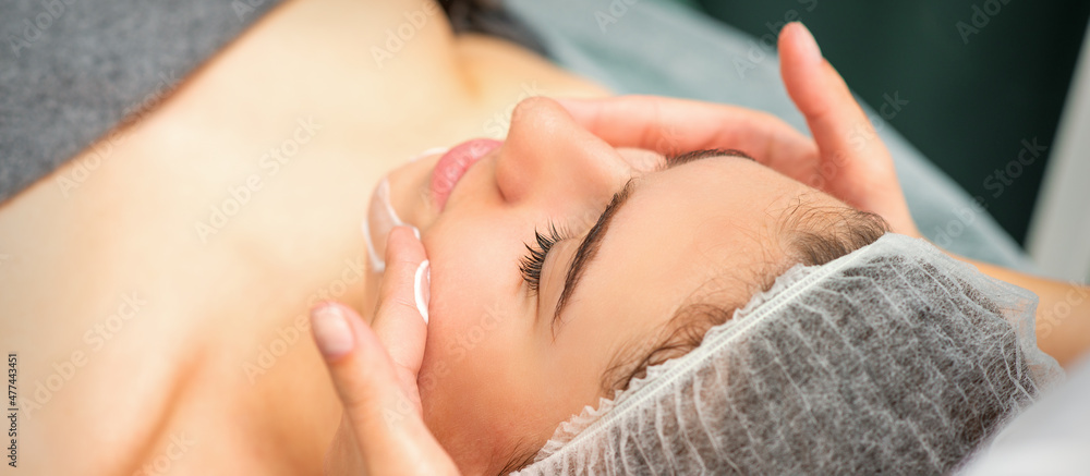 Spa facial skincare. Close-up of a young caucasian woman getting spa moisturizing face massage treatment at beauty spa salon