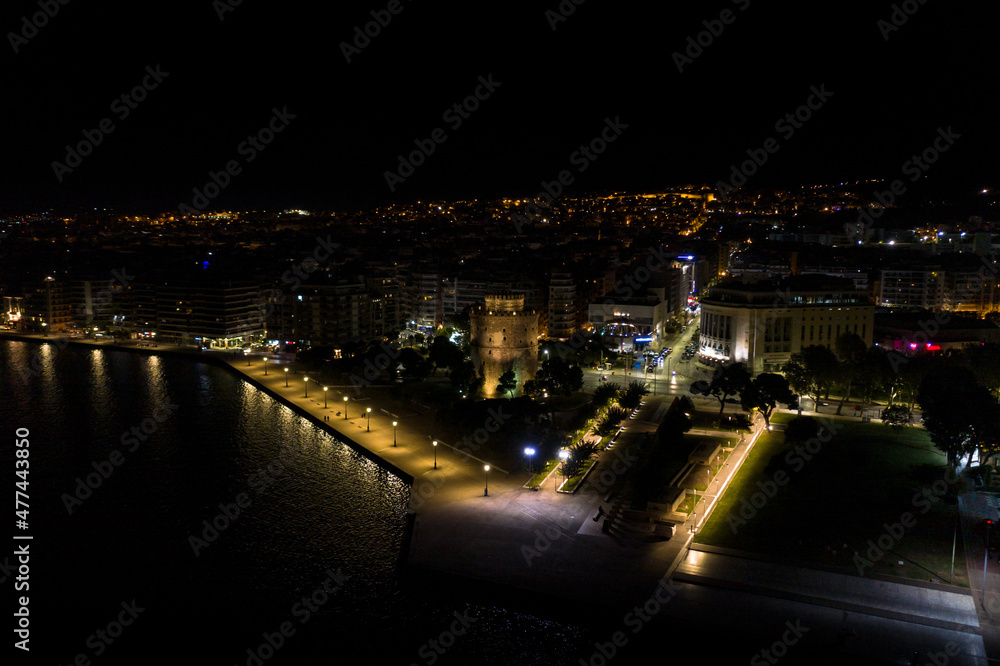 Aerial view of the city of Thessaloniki at night with famous White Tower in the background.